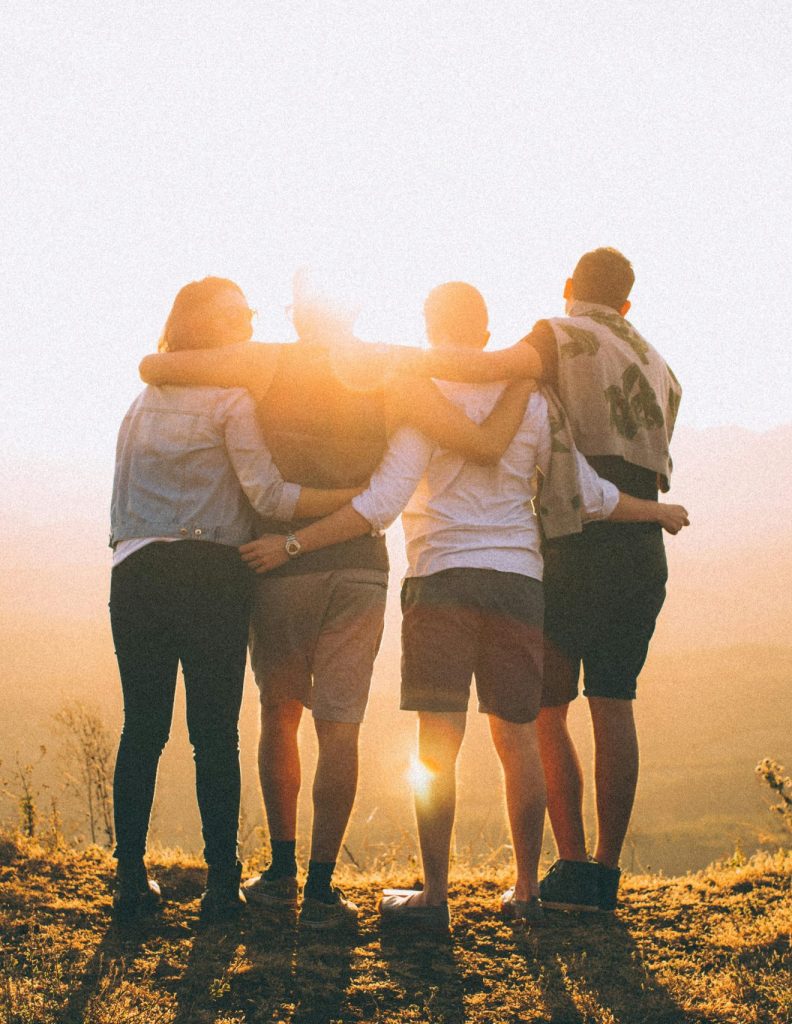 A group of friends embrace while enjoying a breathtaking sunrise over the Brazilian highlands.