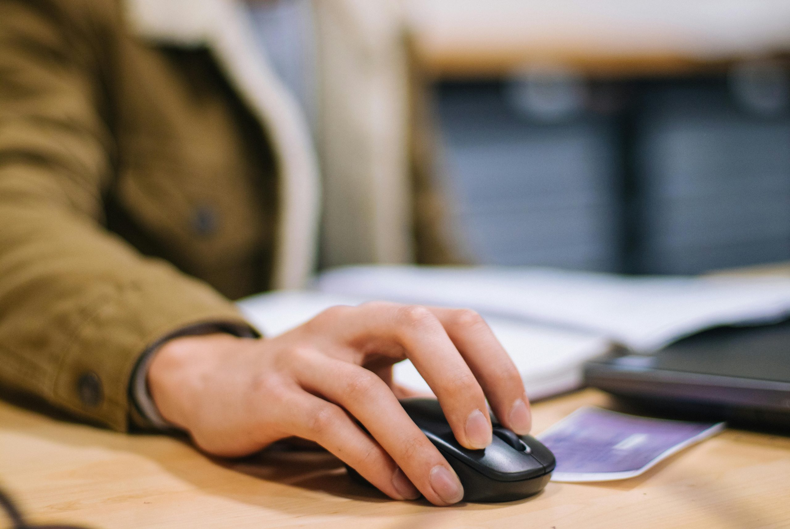 Focused shot of a hand operating a wireless mouse indoors at a desk.